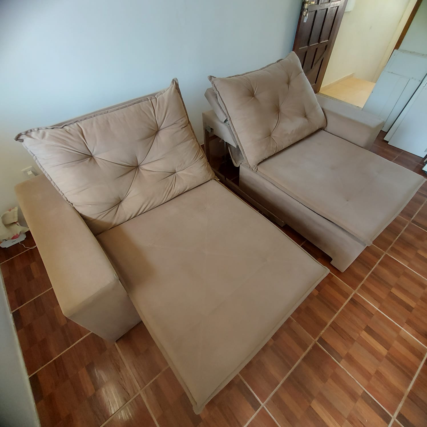 Sofá retrátil bege em uma sala com piso marrom