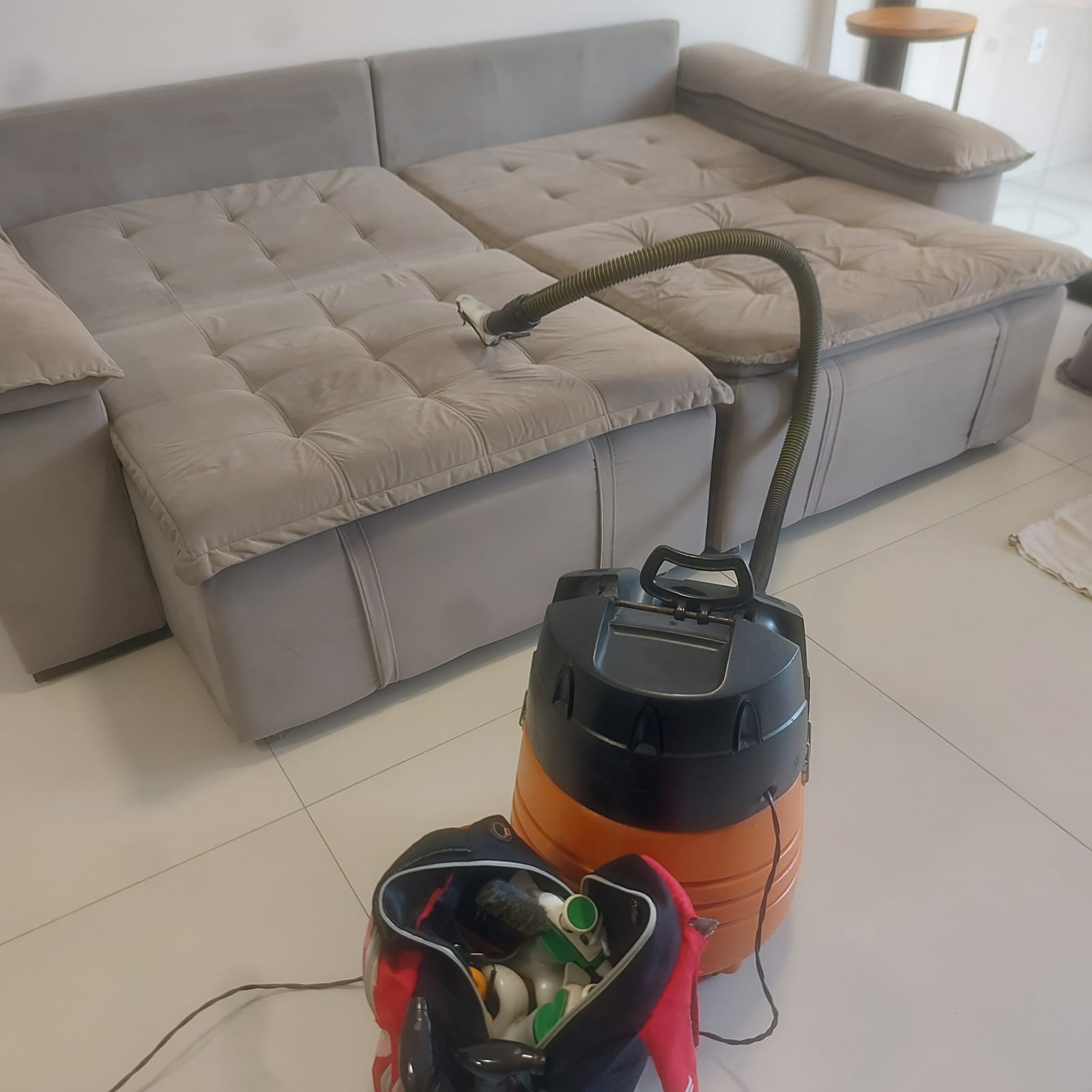 Sofá cinza com equipamento de extração durante atendimento em domicílio